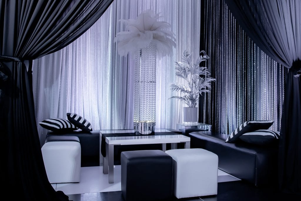 luxurious seating area at black & white party. Features chiffon drape, ottomans, and a feather centrepiece Black & White style decorating ideas