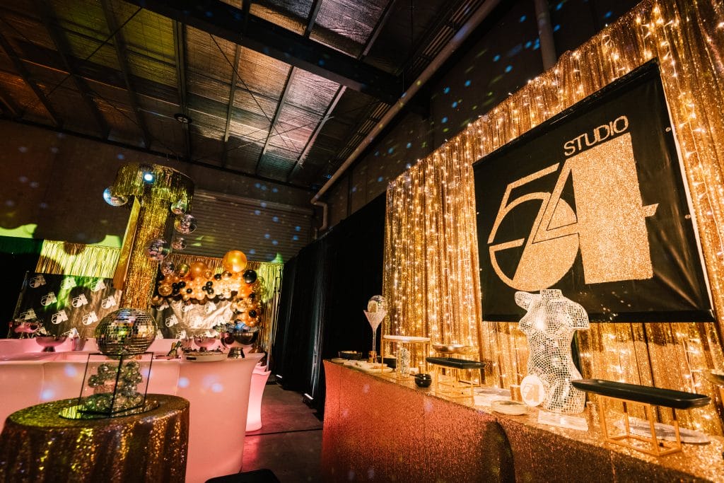 glamorous gold studio 54 themed party with themed props and gold draping From Empty Warehouse to Studio 54 Party