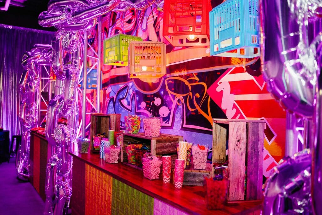 Graffiti themed party setup candy buffet, crates, pendant lights, themed backdrop