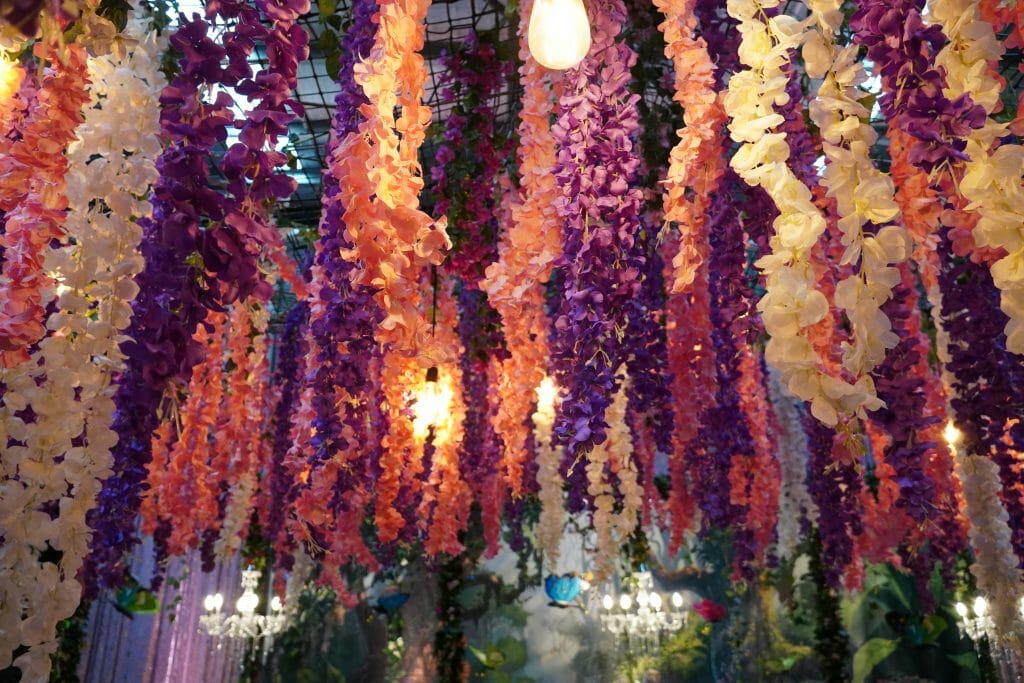 hanging artificial flowers in an enchanted garden themed event