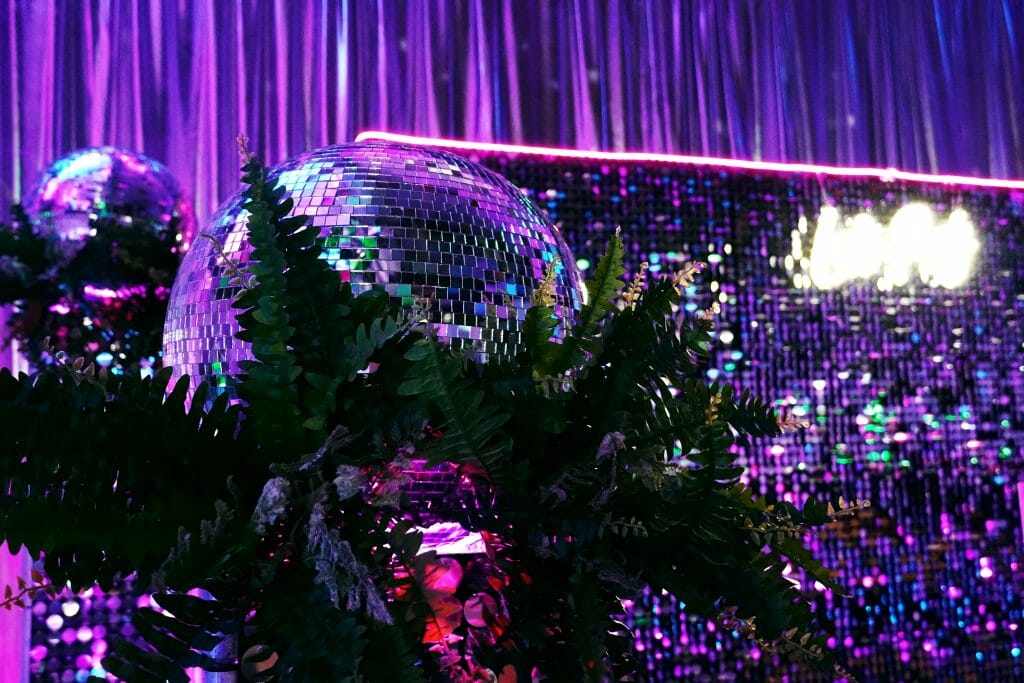 mirror balls, greenery, sequin panels, neon lights, neon sign at neon disco party theme 10 popular party themes for 2023