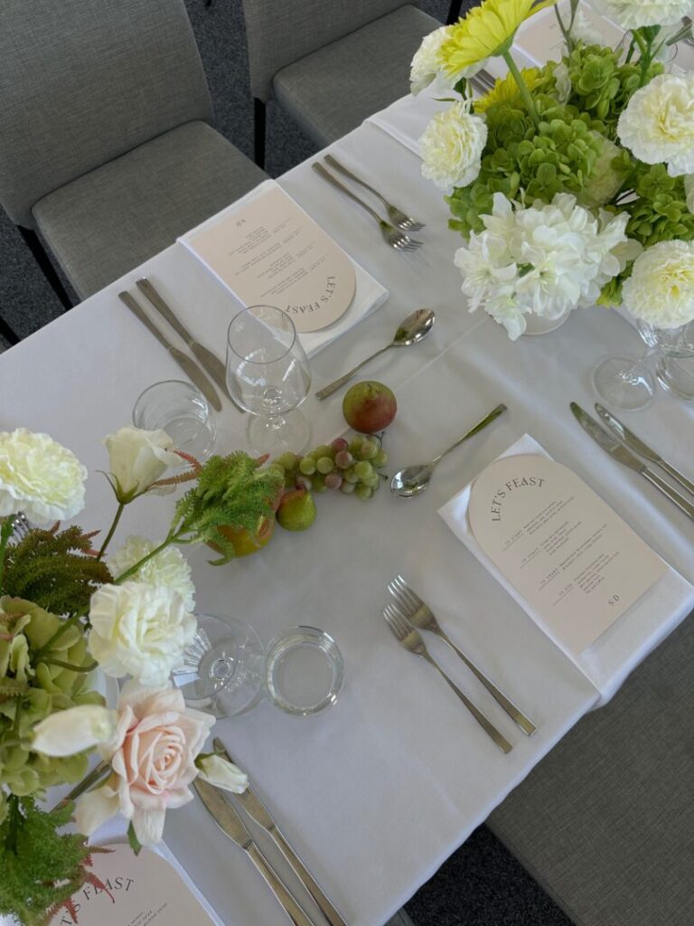 Wedding reception table setup with white linen, contemporary florals