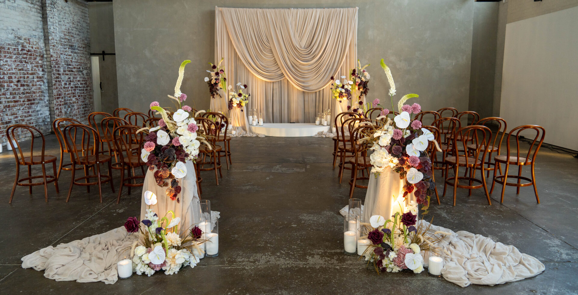 Wedding ceremony setup with scalloped drape, draped plinths with moody, contemporary florals wedding decorating melbourne wedding ceremony decorating melbourne