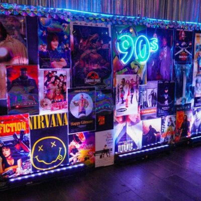 90s neon sign sitting on a backdrop of 90s movie posters