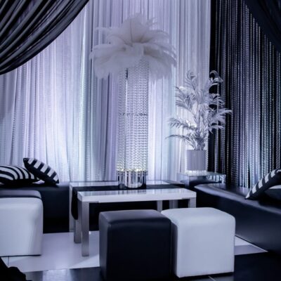 luxurious seating area at black & white party. Features chiffon drape, ottomans, and a feather centrepiece Black & White style decorating ideas