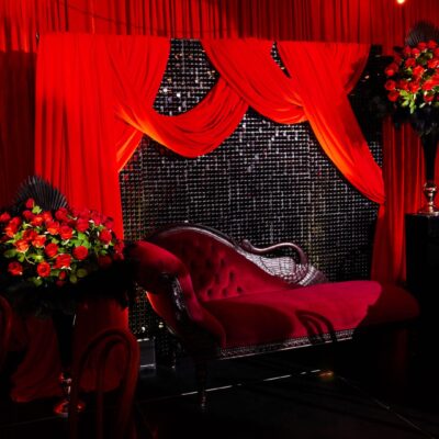 black sequin panel backdrop, red velvet drape, roses, red loveseat welcome to burlesque