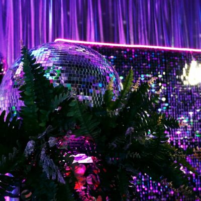 mirror balls, greenery, sequin panels, neon lights, neon sign at neon disco party theme 10 popular party themes for 2023