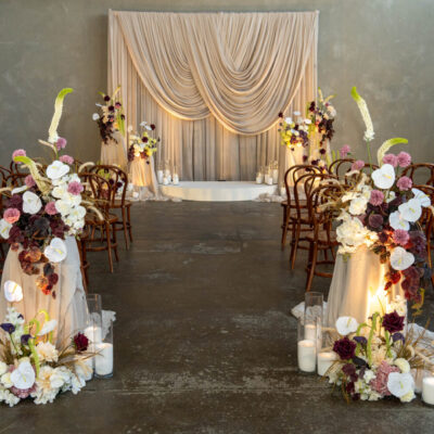 Wedding ceremony setup with scalloped drape, draped plinths with moody, contemporary florals wedding decorating melbourne wedding ceremony decorating melbourne