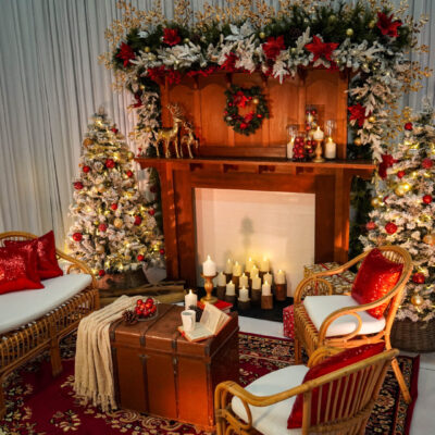 christmas themed setup featuring white frosted pine trees, ornaments, rattan furniture, and red cushions christmas decorating ideas