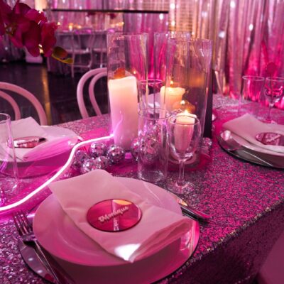 Pink disco dinner party table setup. Featuring custom signage, silver sequin table overlay, and various pink and silver styling items pink disco theme walkthrough