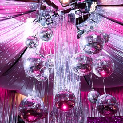 silver mirror balls, silver tinsel, silver drape, pink lighting pink disco theme decorating essentials