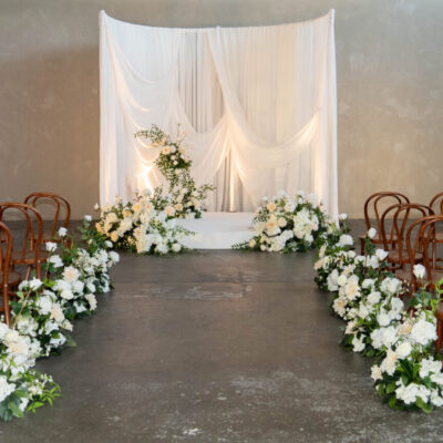 classic romance wedding style - Fabrik venue white gathered drape, white florals and greenery, white ceremony stage, bentwood chairs wedding ceremony setup melbourne