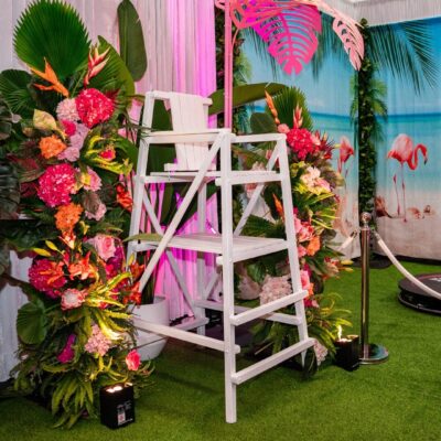 White lifeguard chair with tropical floral and greenery installations on either side